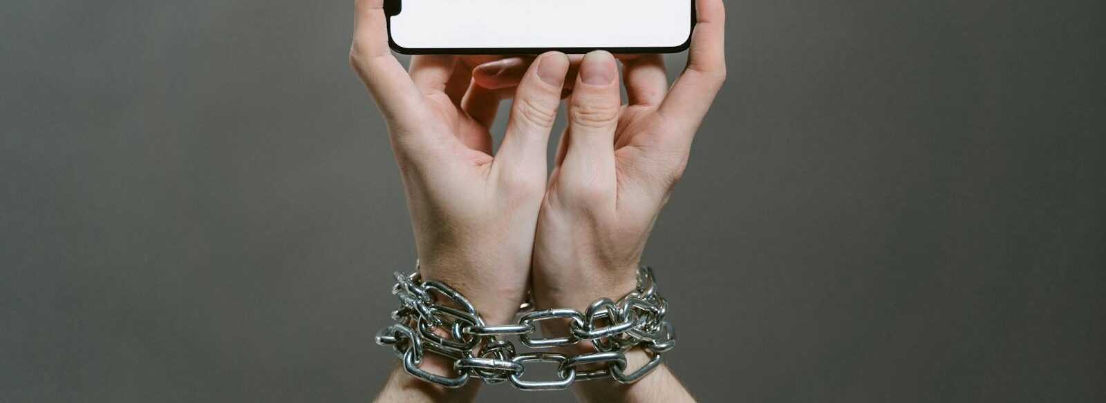 Conceptual image of a person holding a smartphone labeled 'GAMERS' with chained hands.